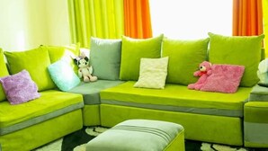 A bright green sectional sofa with multiple cushions and a pink teddy bear on it. - JKIA Tours and Homes (Syokimau)