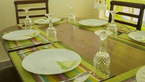 A dining table set with plates, cutlery, and glassware, surrounded by chairs. - JKIA Tours and Homes (Syokimau)
