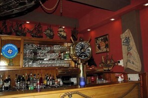 A bar with a clock, shelves of bottles, and a red wall with ship decorations. - Gasthaus Kehrwieder (Wunstorf)