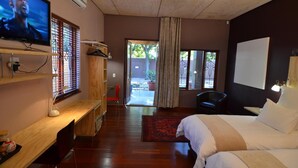 Un dormitorio con cama, televisor, escritorio y vistas al exterior.
