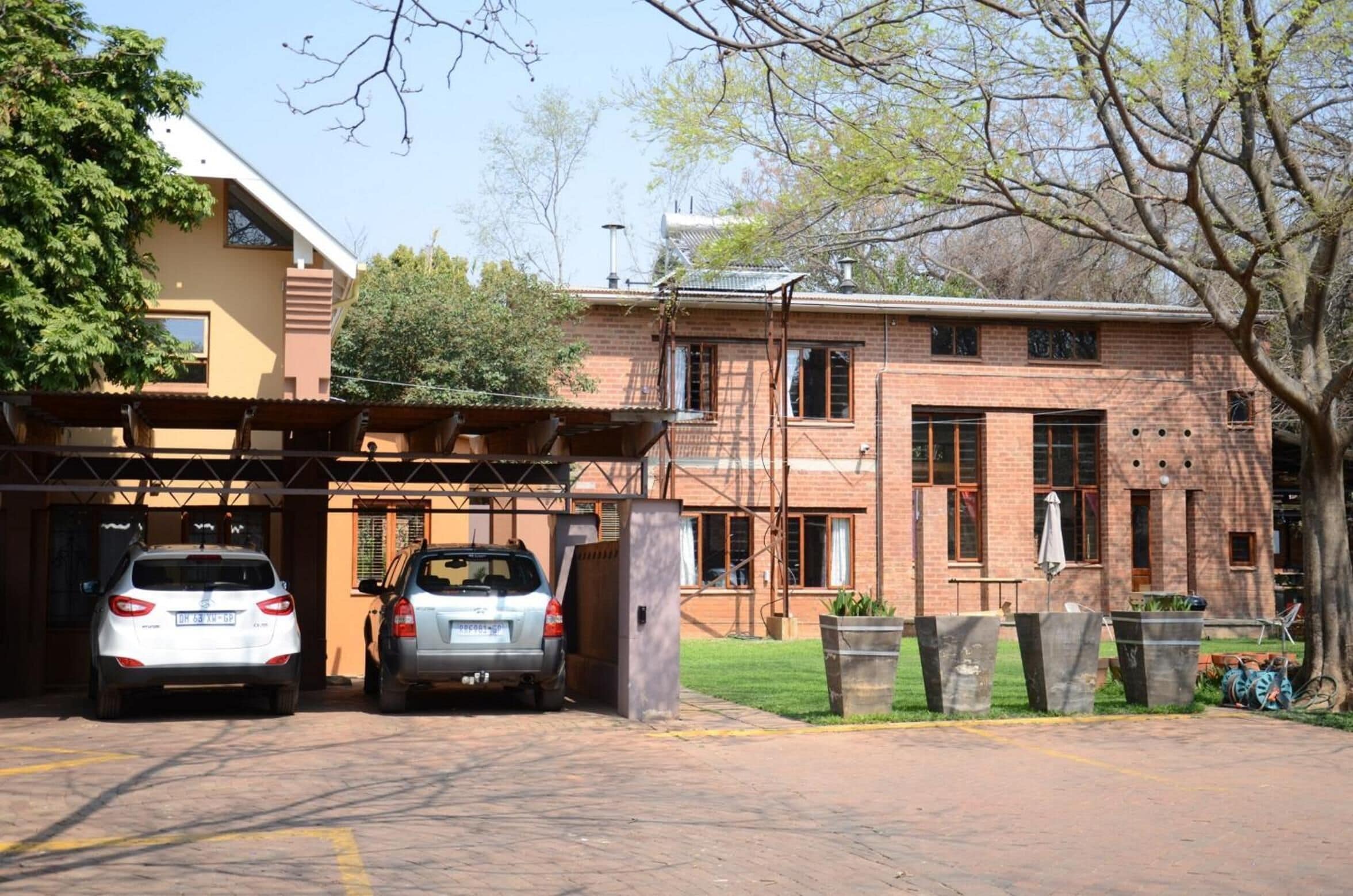 A parking area with two cars, a brick building with windows, and a tree.