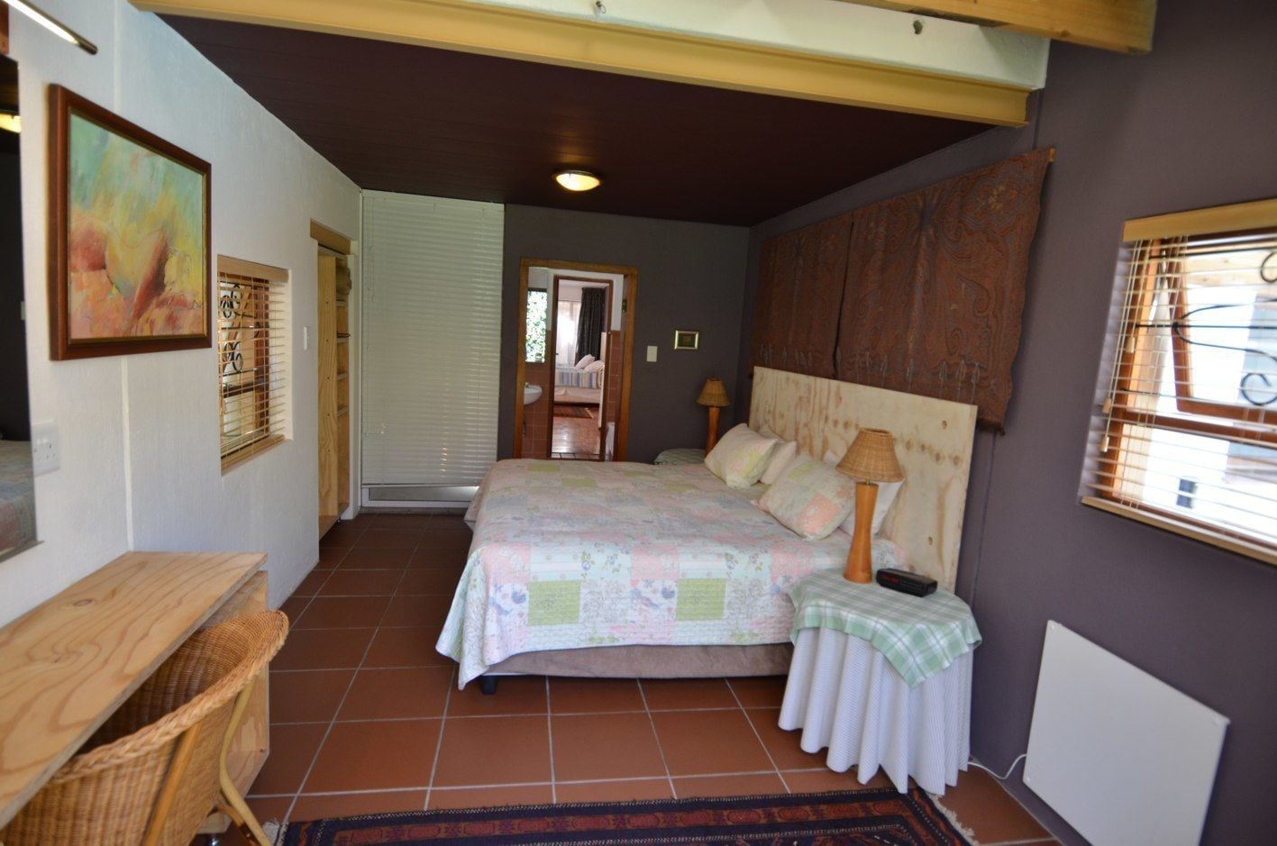 Un dormitorio con cama, lámpara de noche y escritorio con silla.