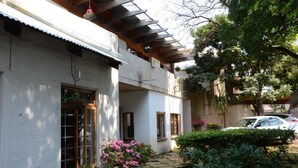 Un patio con un edificio blanco, plantas en macetas y un coche aparcado.