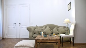 A room with a sofa, a wooden coffee table, a chair, a lamp, and a door. - ✺ Guest's Favorite part of Tbilisi City (Dzveli Tbilisi)