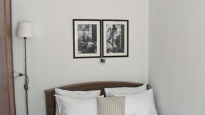 A neatly made bed with white linens and a wooden headboard, a floor lamp, and two framed pictures on the wall. - ✺ Guest's Favorite part of Tbilisi City (Dzveli Tbilisi)
