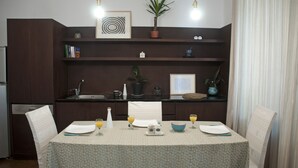 A dining area with a table set for two, a kitchen in the background, and a potted plant on the shelf. - ✺ Guest's Favorite part of Tbilisi City (Dzveli Tbilisi)
