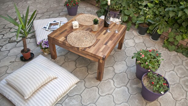A wooden table with woven placemats, two potted plants, a candle, and two wine glasses on a tiled patio. - ✺ Guest's Favorite part of Tbilisi City (Dzveli Tbilisi)