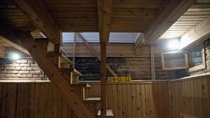 A wooden interior with a staircase, a brick wall, and a window with a metal mesh. - ✺ Guest's Favorite part of Tbilisi City (Dzveli Tbilisi)