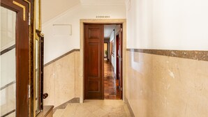 A hallway with a wooden door labeled "ESQUERDO" leading to a room. - Central 4-Bedroom Apartment in Santa Catarina (Oporto)