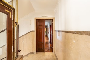 Un couloir avec une porte en bois portant l’inscription « ESQUERDO » qui donne accès à une pièce.