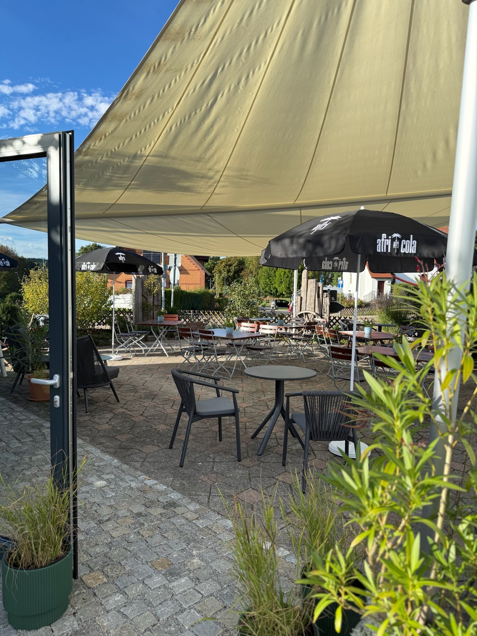 An outdoor seating area with tables and chairs under a large canopy.