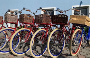 Una hilera de bicicletas antiguas con cestas de mimbre y una caja de madera etiquetada 'BRAVE CLASSICS' a la derecha.