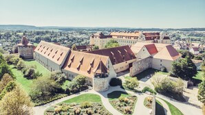 A castle complex with multiple buildings, a moat, and surrounding greenery. - ApartHotel Rose Ellwangen (Ellwangen)