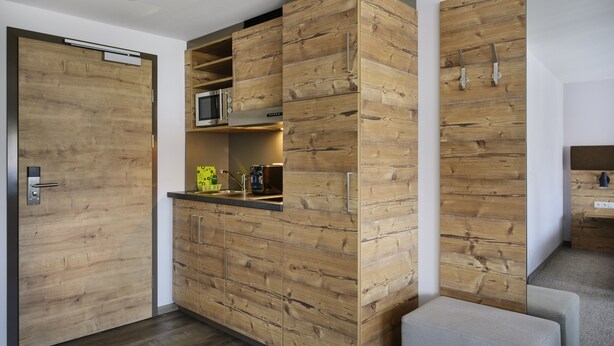 A modern kitchen with wooden cabinetry, a microwave, and a coffee machine. - ApartHotel Rose Ellwangen (Ellwangen)
