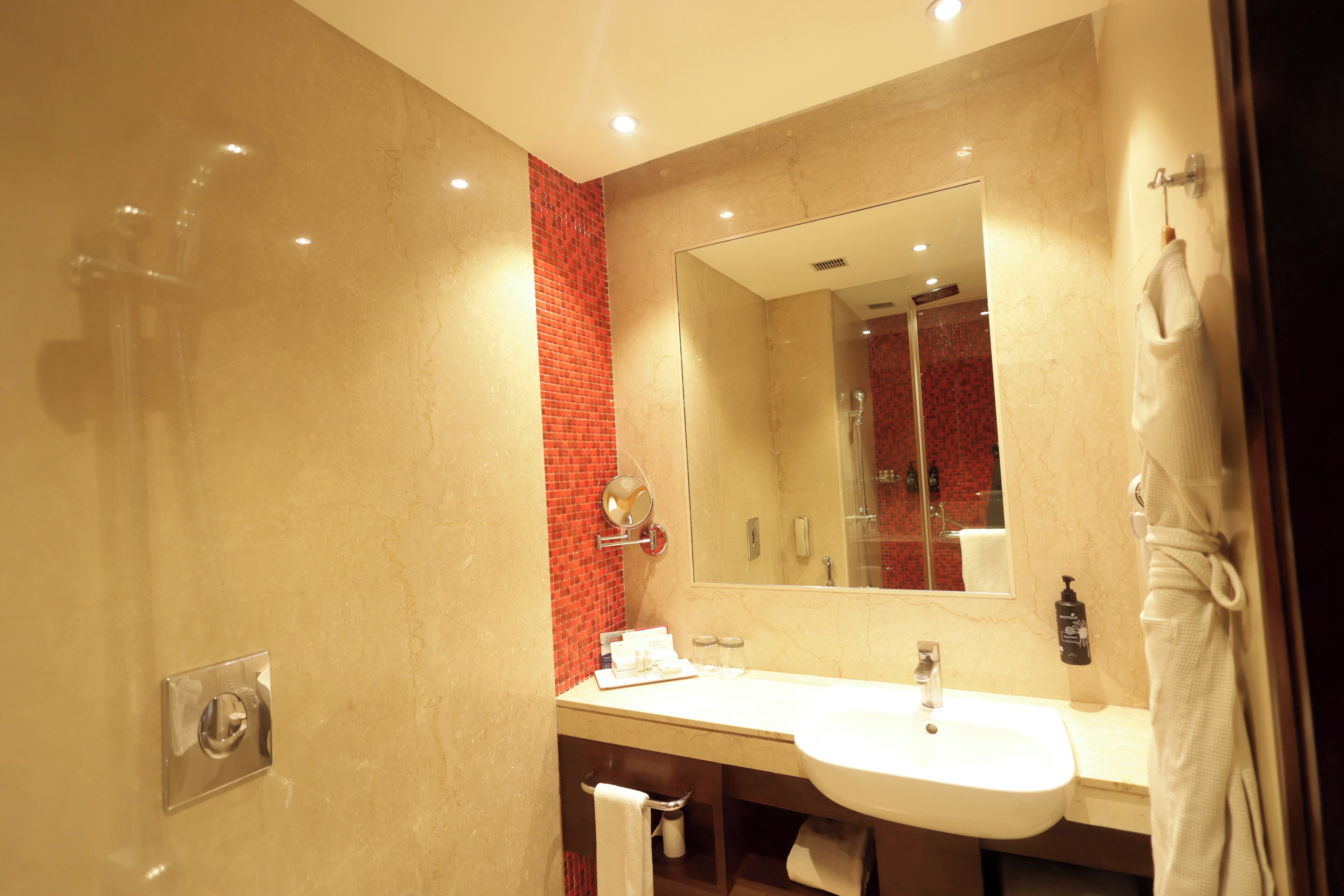A modern bathroom with a large mirror, a sink, and a shower.