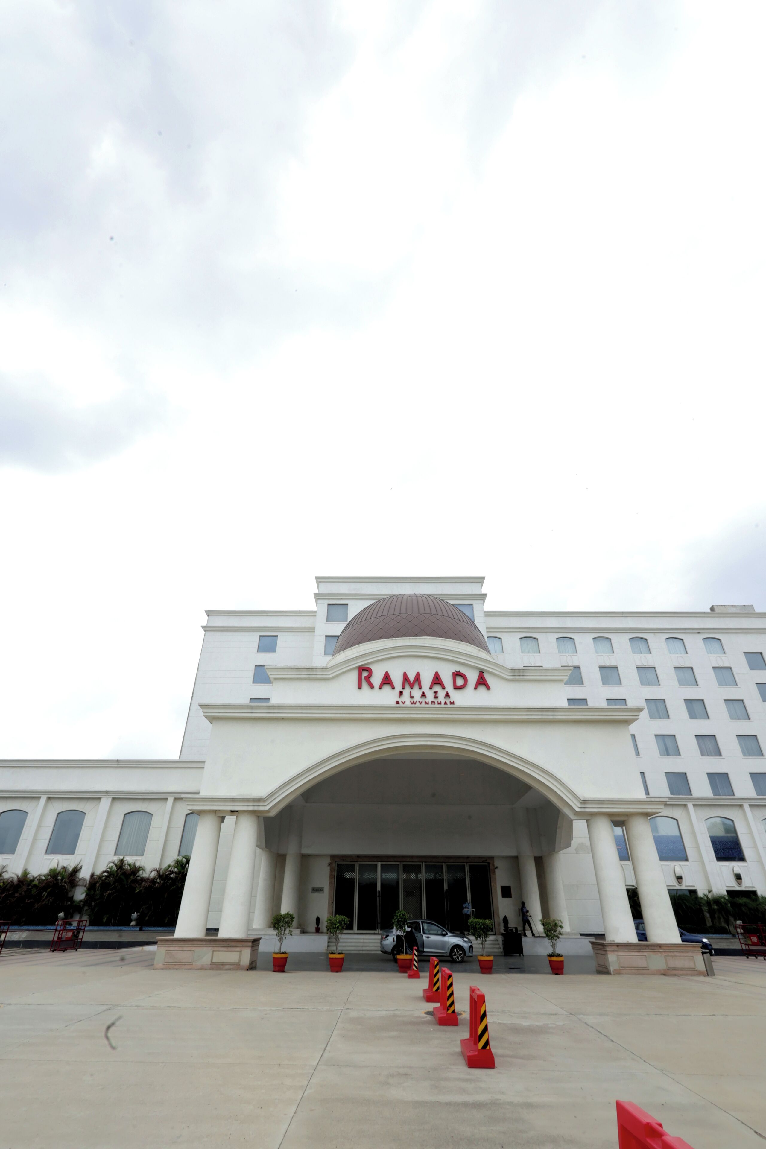 Um edifício grande e branco com uma cúpula, e a palavra "RAMADA" exibida em destaque.