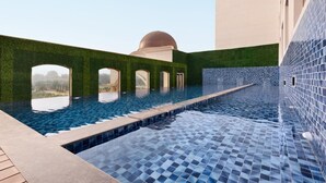 An infinity pool with a clear view of the sky and a dome structure in the background.