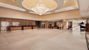 A spacious lobby with a grand chandelier, a reception desk, and a seating area.