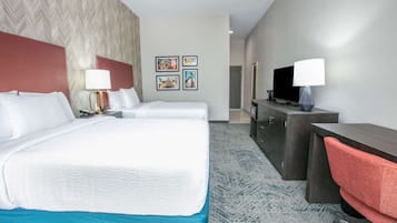 Habitación de hotel con una cama grande, dos mesitas de noche, un escritorio con silla, televisor y una obra de arte en la pared.