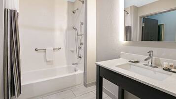 Un baño moderno con bañera, lavamanos y espejo.