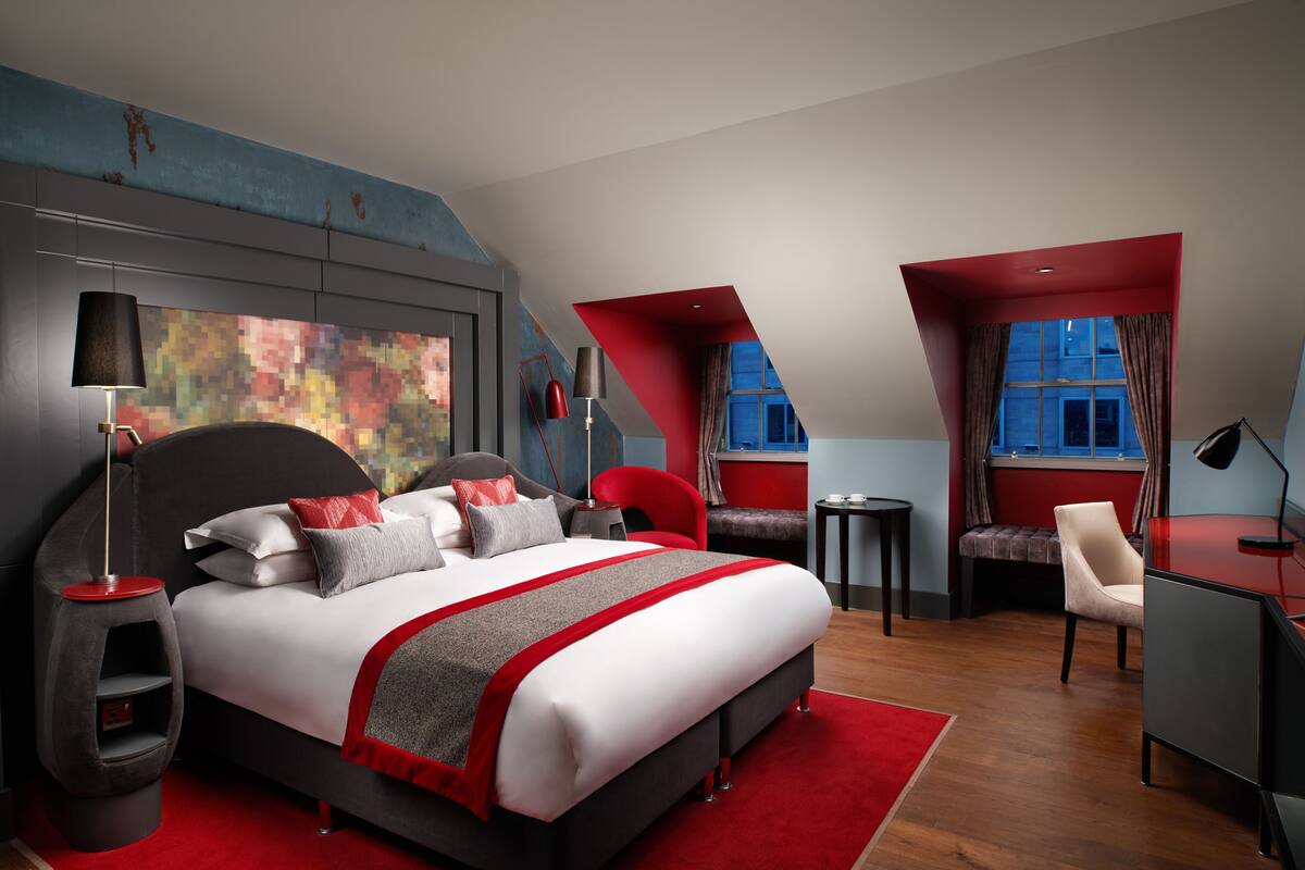 A modern bedroom with a large bed, a desk, and a chair.