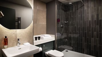 A modern bathroom with a large mirror, a sink, a toilet, and a glass-enclosed shower area.