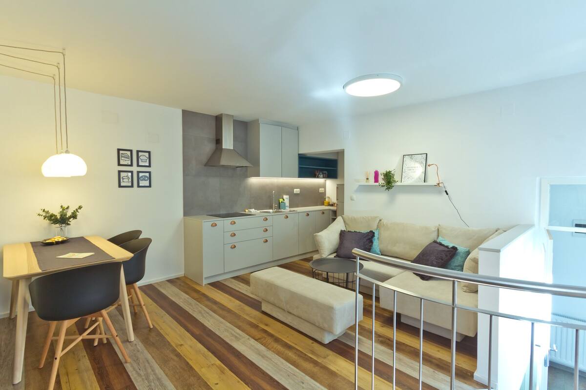 A modern apartment with a dining area, kitchenette, and living space.