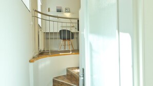 A staircase with wooden steps leading to a landing with a chair and a small shelf with decorative items. - City Centre Apartments (Ljubljana)