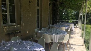 Een terras met ronde tafels gedekt voor een maaltijd, omringd door stoelen en bedekt met witte tafelkleden.