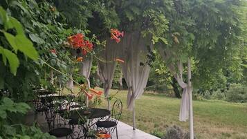 An outdoor patio with a patterned rug, metal chairs, and a table.