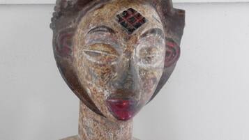 Une sculpture à la texture rugueuse, dont la tête est ornée d’un motif.