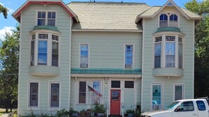 A two-story house with a central entrance, bay windows, and a red door.