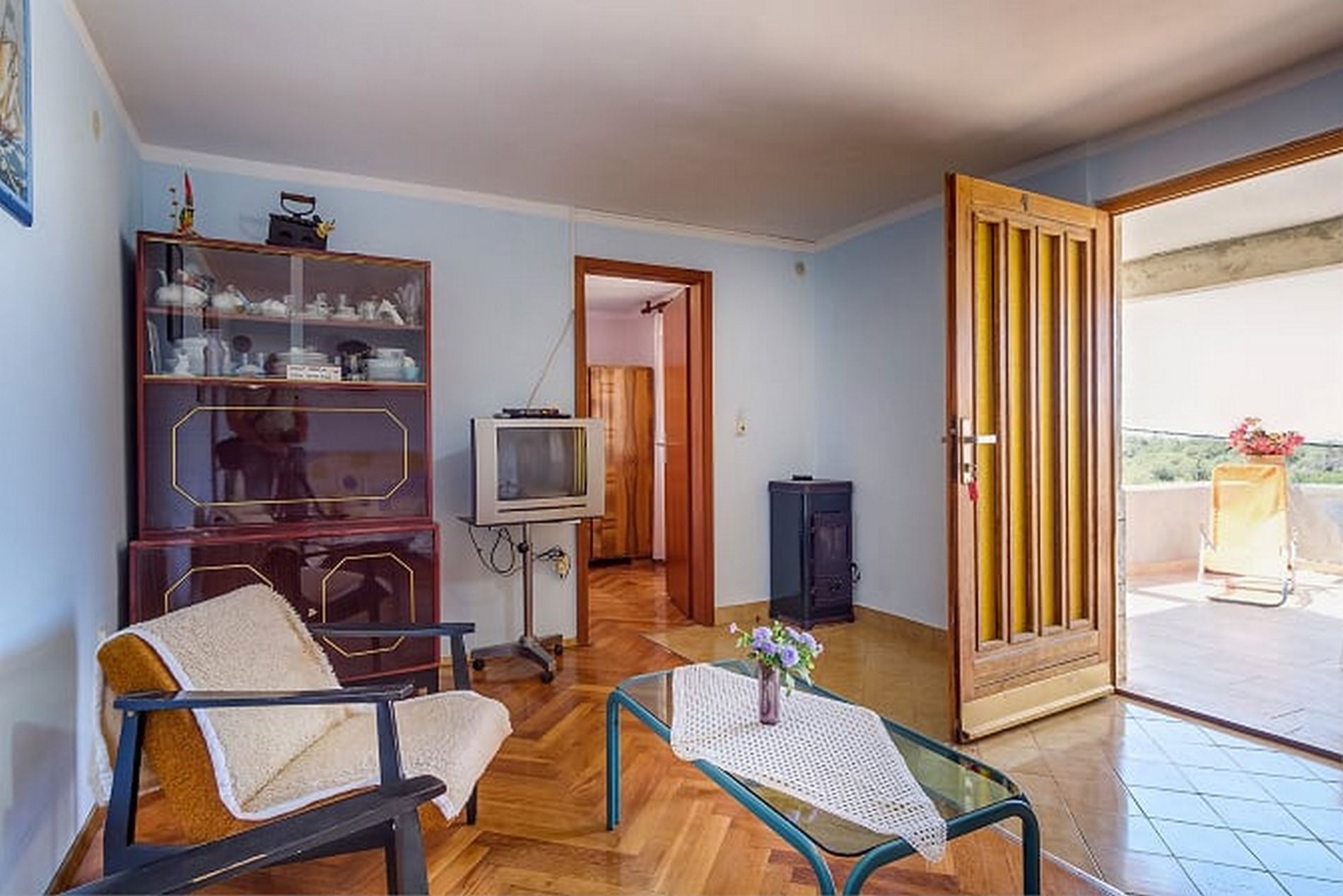 Un saló amb un sofà, una taula de centre de vidre, una televisió i un moble.