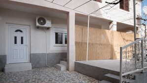 A building entrance with a tiled floor, a white door, a window, and a wooden wall. - Andrea&Leon Apartments (Mali Losinj)