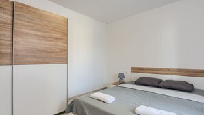 A bedroom with a bed, pillows, a nightstand, a lamp, and a wardrobe. - Andrea&Leon Apartments (Mali Losinj)