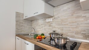 A modern kitchen with a wooden countertop, stainless steel appliances, and a stone backsplash. - Andrea&Leon Apartments (Mali Losinj)