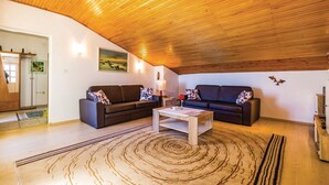 Een gezellige woonkamer met twee donkere banken, een houten salontafel en een tapijt met dessin.