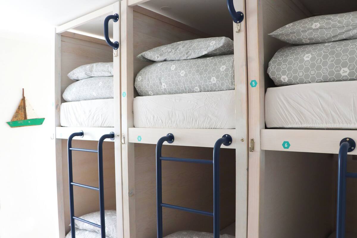 A bunk bed with two levels, each with a mattress and pillows. There are two ladders for access.