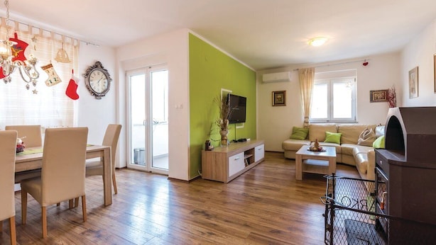 A living room with a wooden floor, a green accent wall, a sofa, a coffee table, and a fireplace. - Apartments Franjkovic (Novi Vinodolski)