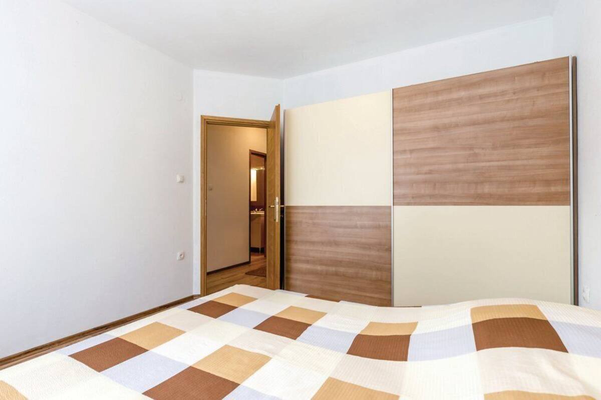 A bedroom with a bed, a wardrobe, and a door leading to another room.