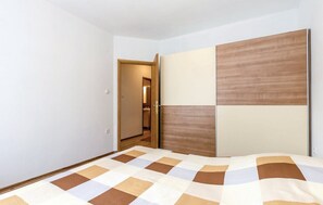 A bedroom with a bed, a wardrobe, and a door leading to another room. - Apartments Franjkovic (Novi Vinodolski)