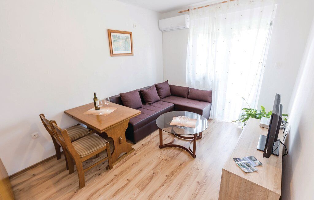 Un soggiorno con tavolo da pranzo in legno, due sedie, un divano, un tavolino in vetro e una TV su un mobile in legno.