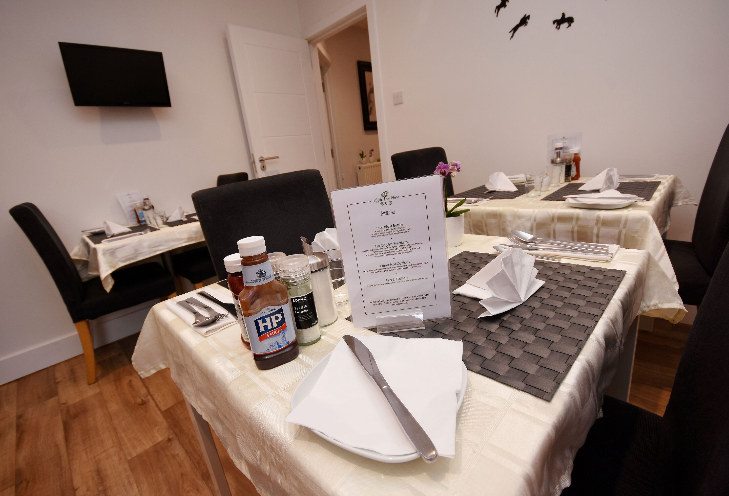 A hotel dining area with tables set for breakfast, including condiments and a menu.