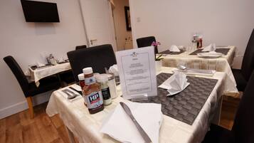 A hotel dining area with tables set for breakfast, including condiments and a menu.