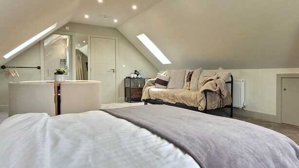 A bedroom with a bed, a vanity, a dresser, a sofa, a television, and a skylight. - Apple Tree Place B&B (Tadley)