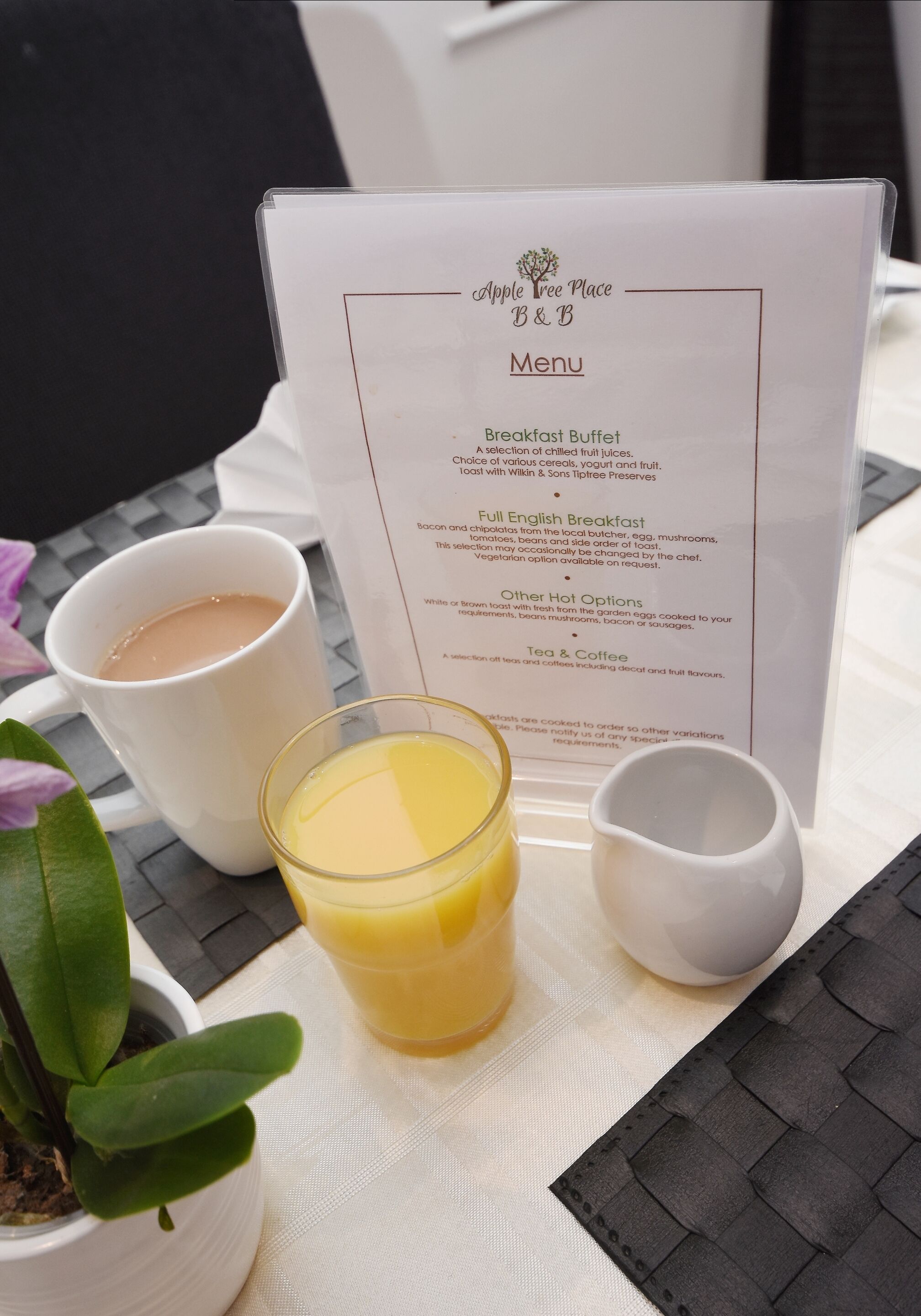Un menu présentant des options pour le petit-déjeuner et deux tasses blanches posées sur une table.
