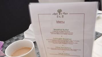 Un menu présentant des options pour le petit-déjeuner et deux tasses blanches posées sur une table.