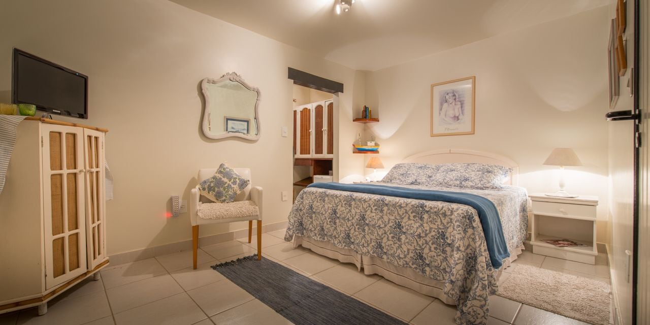 Une chambre à coucher comprenant un lit, une chaise, une télévision, une armoire et un miroir.