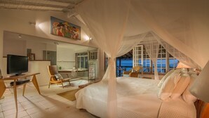 Un dormitorio con cama con dosel, televisión y escritorio con sillas.