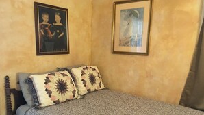Un dormitorio con una cama, dos almohadas, un cabecero y dos cuadros en la pared.